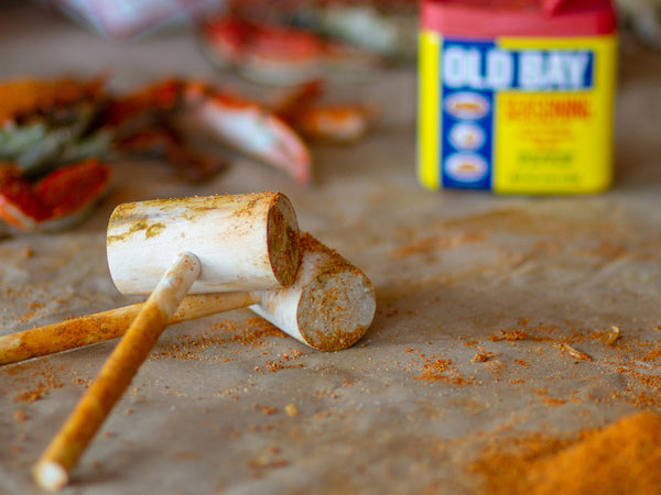 two wooden hammer with old bay seasoning at the background and old bay powder on the board
